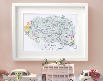 May include: A framed map of North London with floral accents, a pink double-decker bus, and two white toy cars decorated with flowers.