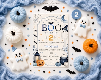 May include: A rectangular birthday invitation card featuring the text Our Little Boo Is Turning 2 for Thomas, surrounded by illustrations of ghosts, pumpkins, bats, a lantern, and a cauldron, accented by small pumpkins and ghost-shaped cookies.
