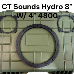 May include: An olive green hard-shell protective case featuring a large circular black gasket in the centre and two smaller circular black gaskets positioned above it. The text CT Sounds Hydro 8" W/ 4" 4800 is printed in black above the case.