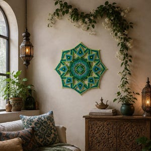 May include: A geometric wall art piece crafted from vibrant green, teal, and blue yarn, featuring a complex star-shaped mandala pattern with sharp, angular lines and a bright lime green border, mounted centrally on a plain, light-colored wall.