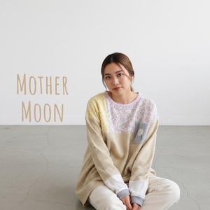 以下が含まれることがあります： ベージュ、イエロー、ピンクの花柄を組み合わせたパッチワークデザインの長袖プルオーバーシャツ。グレーの胸ポケットには小さな白い花のアップリケが施され、ラベンダー色のネックラインと白い袖口が特徴です。MOTHER MOONという文字が書かれています。