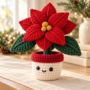 May include: A crocheted poinsettia plant with vibrant red petals and dark green leaves. The center features three small yellow spheres. The plant is housed in a cream-colored crocheted pot with a red rim, featuring two black eyes and a stitched smile.