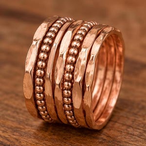 A close-up image of a stack of copper-colored rings with a textured, metallic appearance.