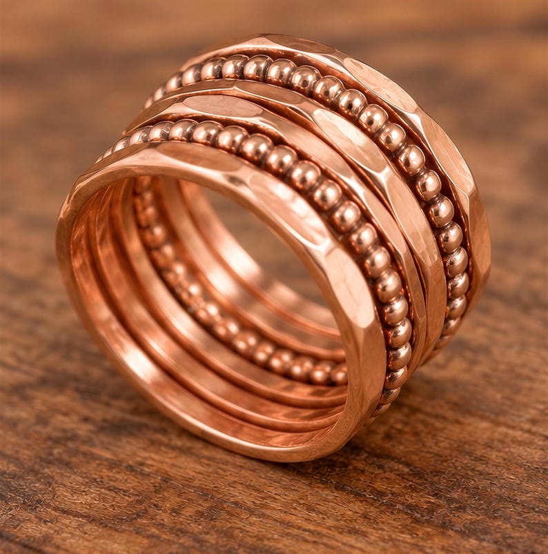 A close-up image of a copper-colored ring with a textured surface, featuring a series of concentric bands with small beads.