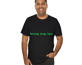 May include: A black short-sleeved t-shirt featuring the text Resting Greg face printed in bright green, sans-serif lettering across the center of the chest. The garment has a classic crew neckline and a standard fit construction.