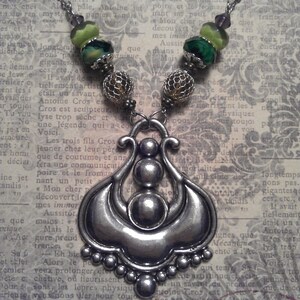 Ornate Silver Metal Statement Pendant with Various Green Glass Bead Accents on Necklace.