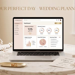 May include: A laptop displaying a digital wedding planner dashboard with a countdown of 125 days, budget charts, and guest RSVP status. The screen shows the text Wedding Planner. A gold tray with two rings and a wedding invitation are nearby.