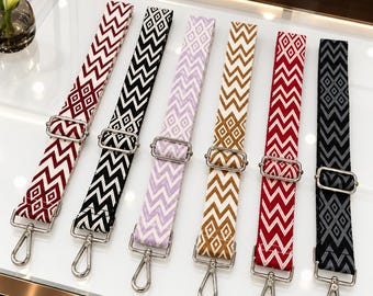 May include: Six adjustable bag straps featuring a repeating geometric chevron and diamond pattern. Each strap is made of woven fabric in various colors including maroon, black, light purple, mustard yellow, and red, with silver metal hardware.