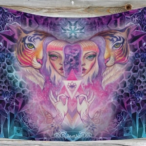 Pode incluir: Uma tapeçaria com um design surrealista e vibrante. Duas faces de tigre ladeiam uma imagem central de duas mulheres com cabelo loiro. A obra de arte incorpora formas geométricas, uma flor de lótus e uma paleta de cores roxo, rosa e azul-petróleo.