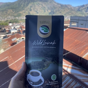 May include: A black coffee pouch labelled Tarzzan Wild Luwak Spesial Blend Coffee Arabika with a net weight of 120g. The packaging features a graphic of a white coffee cup, a lake landscape, and a circular logo with a mountain silhouette.