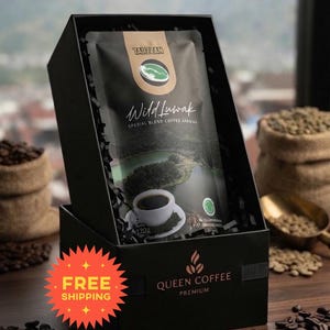 Op de afbeelding: Een zwarte geschenkdoos met een zakje van 120g Tarzzan Wild Luwak koffie. Het zakje bevat een landschapsafbeelding, een kopje koffie en de tekst Wild Luwak Spesial Blend Coffee Arabika. De doos is gelabeld met Queen Coffee Premium.