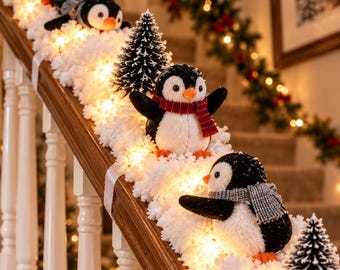 May include: A staircase garland featuring three plush penguin figurines, each wearing a knit scarf, interspersed with miniature artificial pine trees and warm white string lights nestled within a thick layer of white faux snow.