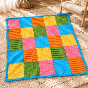 Può includere: Una coperta lavorata a maglia rettangolare caratterizzata da una griglia di quadrati colorati nelle tonalità del rosa, arancione, giallo, verde e blu. Ogni quadrato presenta un motivo a maglia testurizzato unico, inclusi intrecci e rombi.