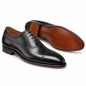 Men’s black leather Oxford shoes with stitched leather sole, cap toe brogue detailing and handcrafted formal dress-shoe finish.