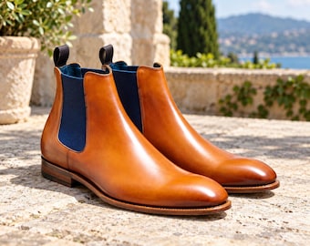 Cognacbruine leren Chelsea boots voor heren, marineblauwe enkellaarsjes met elastische band.
