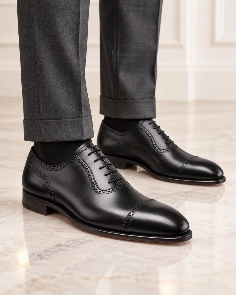 Man wearing black leather cap toe Oxford shoes with tailored trousers, ideal for weddings, business meetings and formal occasions.