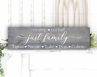 May include: Grey wooden sign with white text that reads "not step, not half, just family". Below the text are the names "David, Nicole, Luke, Pete, Colton" separated by heart symbols.