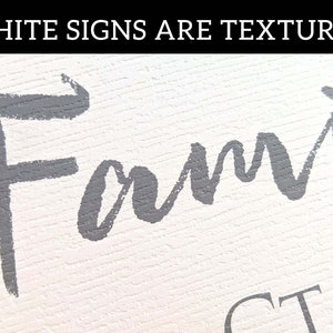 May include: A white sign with the word "Family" written in gray paint. The sign has a textured surface.