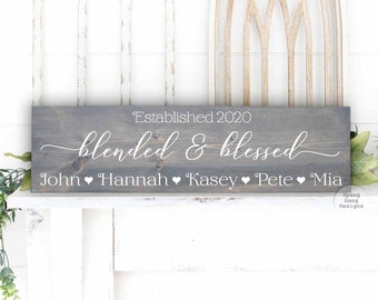 May include: A grey wooden sign with white text that reads "Established 2020 Blended & Blessed John ♥ Hannah ♥ Kasey ♥ Pete ♥ Mia".