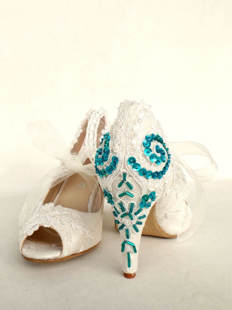 Teal embroidery on the heels of ivory lace wedding shoes.