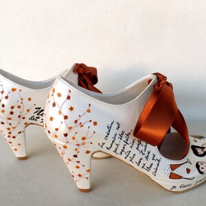 personalized bridal shoes with burnt orange ribbons, fall flowers on the heels, lyrics written on the sides, bride and groom painting on the front.