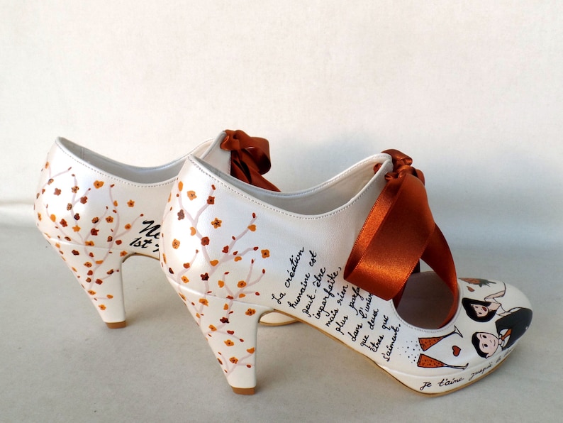 personalized bridal shoes with burnt orange ribbons, fall flowers on the heels, lyrics written on the sides, bride and groom painting on the front.