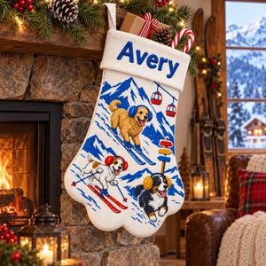 May include: A cream-colored fabric Christmas stocking with a cuff embroidered with the name Avery in blue. The stocking features a colorful graphic of three dogs skiing on a snowy mountain, including a golden retriever, a beagle, and a Bernese mountain dog.