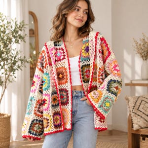 Puede incluir: Un cárdigan de manga larga y frente abierto confeccionado con cuadrados de ganchillo multicolores en tonos rojo, azul, amarillo, verde y morado, unidos por hilo color crema con un borde rojo vibrante en los extremos y puños.