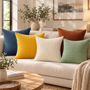May include: A set of five square throw pillows featuring a corduroy texture with a geometric pattern of vertical and horizontal stripes. The pillows are colored in navy blue, mustard yellow, cream, rust orange, and sage green.