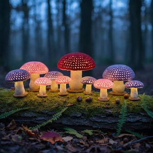 May include: A collection of ten crocheted mushroom-shaped lamps with light-coloured stems and vibrant caps in shades of red, pink, and purple. Each mushroom features a textured, open-weave pattern that glows from within, creating a warm, illuminated display.