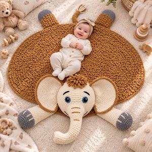 May include: A round, textured, brown crochet play mat shaped like an elephant with a large cream-colored elephant head, trunk, and ears attached to the front. The mat features four dark gray elephant feet and a small tail at the top edge.