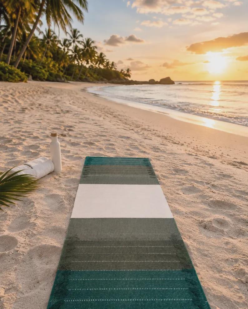 Op de afbeelding: Een rechthoekige yogamat met een kleurblokontwerp in donker bosgroen, olijfgroen en een brede witte middenstreep. De mat heeft een getextureerd oppervlak met subtiele horizontale stikseldetails en franjes aan de uiteinden.