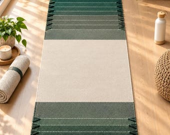 Puede incluir: Una alfombra rectangular tipo pasillero con un gran panel central de color crema flanqueado por dos secciones de color verde oscuro. Las áreas verdes presentan líneas horizontales blancas punteadas y pequeños flecos distribuidos uniformemente.