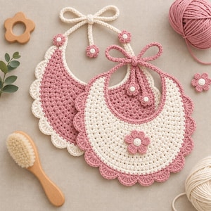 Peut inclure: Deux bavoirs pour bébé au crochet avec un bord festonné et une fermeture à nouer. Un bavoir est principalement rose poudré avec une bordure crème, tandis que l'autre est crème avec une bordure rose poudré. Ornés de petites fleurs au crochet.
