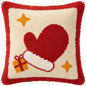 Könnte beinhalten: Ein quadratisches Kissen mit einer strukturierten Schlingenflor-Oberfläche. Das Kissen hat eine cremefarbene Mitte mit einem großen roten Fäustling, einer weißen Manschette, einem kleinen orangefarbenen Geschenk mit roter Schleife und zwei orangefarbenen vierzackigen Sternen, umrandet von Rot.