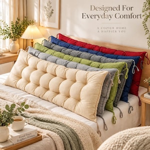 Peut inclure: Une rangée de cinq coussins de banc rectangulaires capitonnés en crème, gris, vert, bleu et rouge, chacun doté de liens en tissu aux coins. Le texte "Designed For Everyday Comfort" et "A COZIER HOME A HAPPIER YOU" est visible au-dessus.