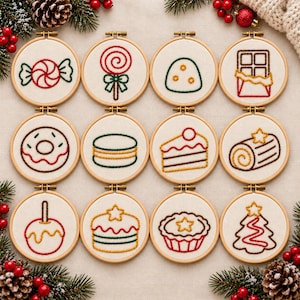 May include: Twelve circular wooden embroidery hoops containing white fabric with stitched designs of holiday sweets including a candy, lollipop, chocolate bar, donut, cake slice, yule log, candy apple, layered cake, tart, and a tree.