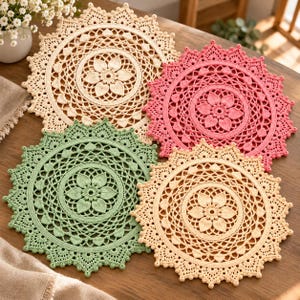 May include: Four circular crochet doilies featuring intricate floral patterns in the centre and scalloped edges. The set includes one cream, one pink, one sage green, and one light yellow doily, each displaying detailed needlework and texture.