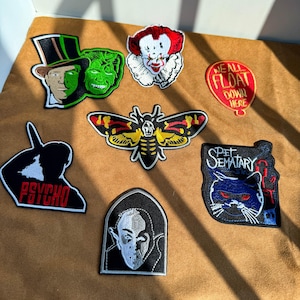 以下が含まれることがあります： ホラーをテーマにした7つの刺繍ワッペン。顔が半分に分かれたキャラクター、ピエロ、WE ALL FLOAT DOWN HEREと書かれた赤い風船、蛾、PSYCHOの文字が入ったシルエット、PET SEMATARYと書かれた猫、そして吸血鬼の刺繍が施されています。
