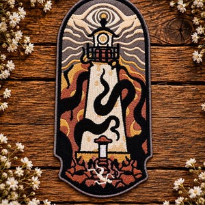 May include: An embroidered patch featuring a lighthouse surrounded by black tentacles. The design includes a large eye at the top, a glowing lantern room, and a rocky base with a small white figure. The colour palette consists of cream, orange, and black.