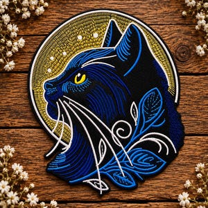 May include: A circular embroidered patch featuring a profile of a black cat with blue highlights and a bright yellow eye. The cat is set against a golden circular background with white dots, and the lower portion includes blue and white leaf motifs.