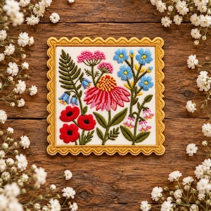 May include: A square embroidered patch featuring a vibrant floral arrangement on a white background, framed by a scalloped mustard yellow border. The design includes red poppies, a large pink coneflower, blue wildflowers, and green ferns.