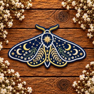 May include: A dark blue embroidered moth patch featuring yellow crescent moons, white star constellations, and green fern-like botanical patterns. The moth has a central starburst design on its thorax and detailed yellow antennae on its head.