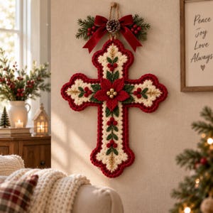 May include: A decorative wall hanging in the shape of a cross, crafted with cream and red yarn. The cross features a central red poinsettia, green leaves, and red berries. A red velvet bow with a pinecone and greenery sits at the top.