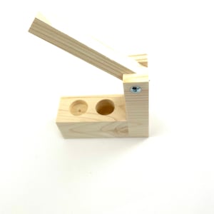 May include: A wooden box with two holes in the top and a hinged lid. The box is made of light wood and has a natural finish.
