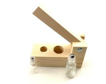May include: A wooden roller bottle holder with two empty glass roller bottles. The holder has two slots for the bottles and a hinged lid.