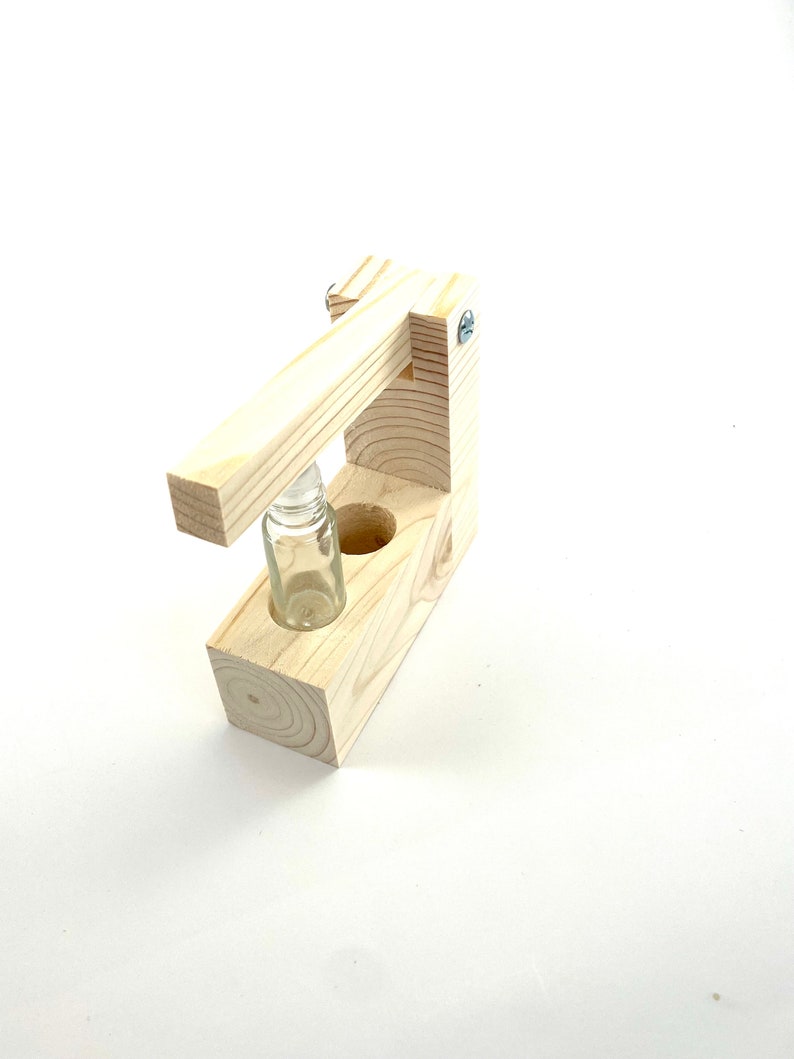May include: A wooden bottle holder with a lever to press down on the bottle. The holder has a clear glass bottle inside.