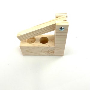 May include: A wooden tool with two holes and a lever. The tool is made of light wood and has a silver screw.