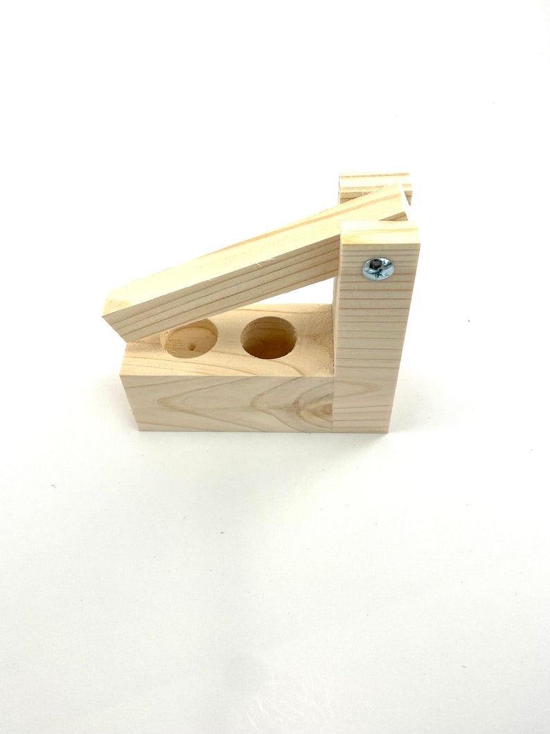May include: A wooden tool with two holes and a lever. The tool is made of light wood and has a silver screw.