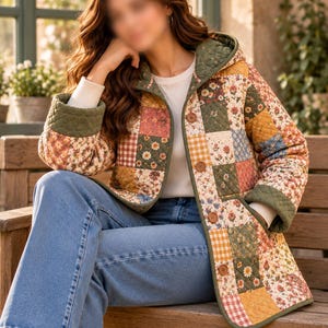K&ouml;nnte beinhalten: Eine gesteppte Jacke mit einem Patchwork-Design aus Blumen- und Vichy-Karomustern in Gr&uuml;n-, Gelb-, Blau- und Rosat&ouml;nen. Die Jacke hat eine Kapuze, lange &Auml;rmel mit olivgr&uuml;nen B&uuml;ndchen und eine Knopfleiste mit braunen Kn&ouml;pfen.
